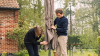 Two people setting up their parasol in their garden