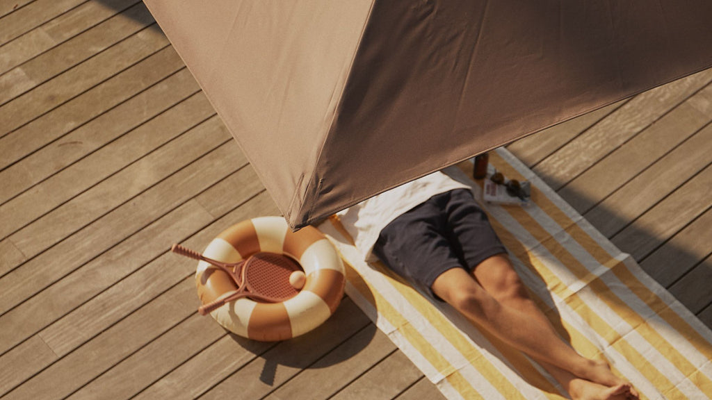 A man taking a nap under his parasol