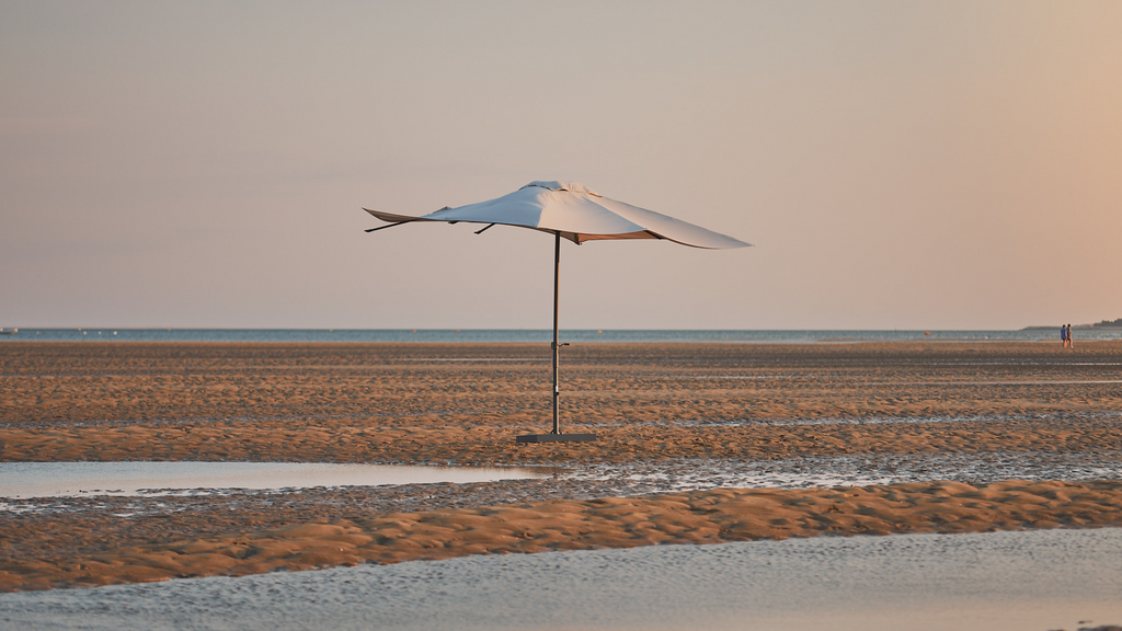 A straight parasol with an ecru canvas on the sand
